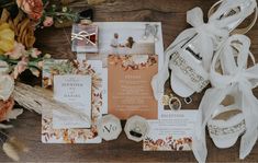 the wedding stationery is laid out on top of the table with flowers and jewelry