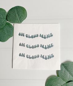 a piece of paper that has some type of writing on it next to green leaves