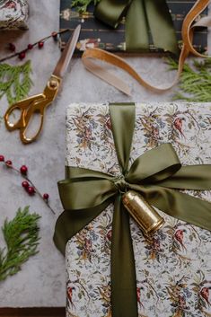 wrapping presents wrapped in green ribbon and gold foil with scissors on the table next to them