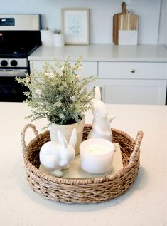 a wicker basket with candles and bunny figurines in it on a kitchen counter