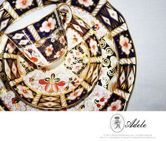 an ornately decorated tea cup and saucer set on a plate with floral designs