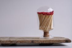 matches are in a glass container on top of a wooden board