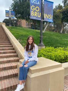 a young woman sitting on the steps in front of a sign