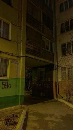 an empty alley with no people or cars on it at night, in front of apartment buildings