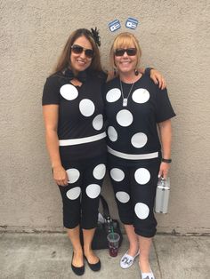 two women dressed in black and white polka dot outfits standing next to each other on the sidewalk