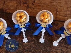 three small glass vases filled with gold colored candies on top of a wooden table