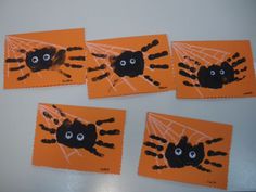 four handprinted pictures of spider on orange paper with black eyes and hands in the center