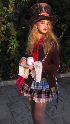 a woman in a skirt and top hat holding a cup