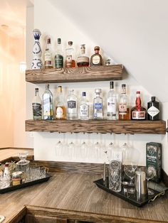 the shelves are full of liquor bottles and glasses on the bar counter in front of the stairs