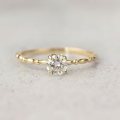 a yellow gold engagement ring with a single diamond in the center, on a white surface