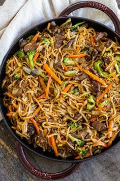 a pan filled with noodles and vegetables on top of a table