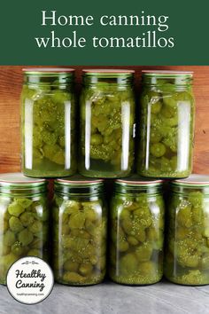 jars filled with pickles sitting on top of a table next to a sign that says home canning whole tomatoes