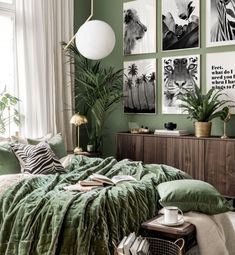 a bedroom with green walls and pictures on the wall above the bed, along with plants