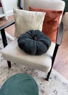 a chair with several pillows on it in a living room