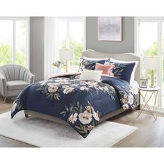 a bed in a bedroom with blue and pink floral comforter sets on top of a white rug