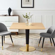 a dining room table with two chairs and a vase on the top, in front of a white wall