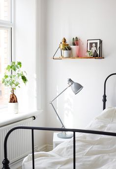 a bedroom with a bed, lamp and pictures on the wall next to window sill