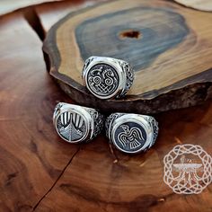 three silver rings sitting on top of a wooden table next to a piece of wood