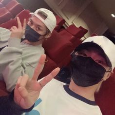 two people wearing face masks and making the peace sign with their hands in front of them