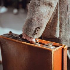 a person holding onto an old suitcase on the street with their hand in it's pocket