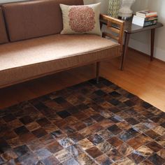 a brown couch sitting on top of a hard wood floor next to a wooden table