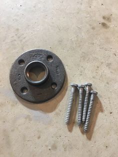 two screws sitting next to each other on top of a table with some nuts