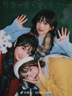 three young women posing for a photo in front of a blackboard with writing on it