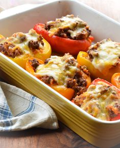 stuffed bell peppers in a casserole dish on a wooden table with a napkin