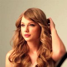 a woman with long, wavy hair combing her hair