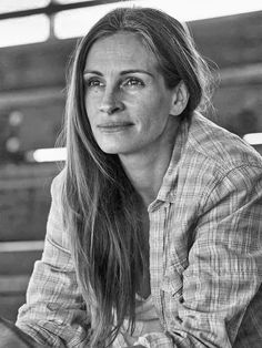 a black and white photo of a woman with long hair sitting in a train station