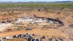 an aerial view of a construction site in the middle of nowhere, with trees and dirt surrounding it