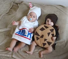 two babies dressed in costumes laying on a blanket