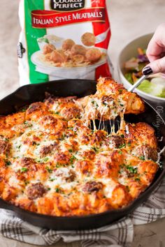 a person is taking a piece of pizza out of the casserole dish with a fork