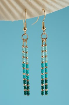 the earrings are made with turquoise beads and gold plated wire, on a blue background