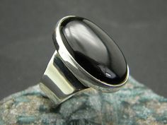 "Black Onyx Ring, Sterling silver Ring, Black big Ring, Oval Black Stone, Artisan modernist ring Statement ring large black onyx Big oval black onyx cabochon stone set in a sterling silver with fine bezel and wide band .This lovely stone 18 mm x 25 mm little less than 1\" inch (0.944\") long. The band starts from 12mm wide and end to 5 mm at the back of the shank I will make the ring from the beggining so don't forget to select your size or if you need another to mention it at check out. I need Modern Black Cabochon Rings, Modern Black Oval Cabochon Ring, Modern Black Oval Cabochon Jewelry, Stone Ring Design, Silver Jewellry, Big Ring, Modernist Ring, Silver Rings With Stones, Sterling Silver Mens Rings