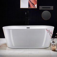 a white bath tub sitting in a bathroom next to a vase with flowers on it