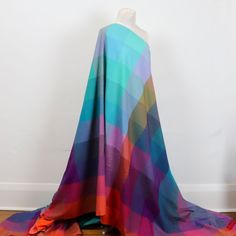 a colorful blanket draped over a mannequin's head on a wooden floor