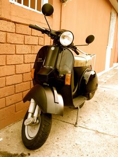 a motor scooter parked on the side of a street next to a brick building