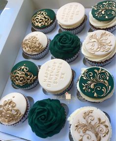 there are many cupcakes in the box with gold and green decorations on them