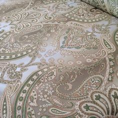 an image of a bed with green and white paisley print on the comforter cover