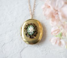 This is a large gold locket necklace. It is made from a vintage oval shaped brass locket and adorned with a beautifully detailed brass leaf wreath and a vintage floral resin cameo. The locket is quit large and holds space for two special photos. Measurements & Details - locket size: 45mmx38mm, gold tone brass - chain: vintage brass chain PERSONALISATION We can personalize this locket by adding 1 or 2 photos for you. You can also choose to add photo (s) on your own. Please choose from drop-do Ornate Oval Locket Necklace From Vintage Collection, Oval Locket Necklace For Vintage Collection, Oval Cameo Necklace Keepsake, Gold Cameo Locket Necklace For Wedding, Oval Cameo Necklace For Keepsake, Oval Cameo Keepsake Jewelry, Brass Medallion Locket Necklace With Cameo, Antique Gold Oval Locket Necklace For Keepsake, Gold Cameo Necklace For Keepsake