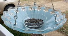 a glass bird feeder hanging from a chain