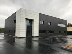 an empty parking lot in front of a large industrial building with two doors and windows