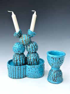 two candles are sitting next to each other in blue vases and bowls with chocolate drizzled on them