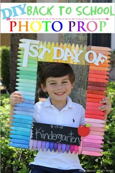 a young boy holding up a sign made out of colored crayons and the words 1st day of school written on it