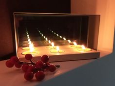 a bunch of candles that are sitting on a table with some berries in front of them