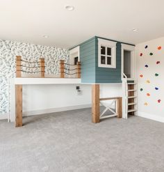 there is a loft bed in the middle of an empty room with climbing wall paper on the walls