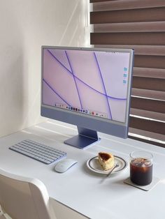 a computer monitor sitting on top of a desk next to a plate of food and drink