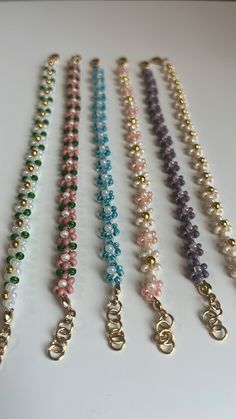 several different colored beads are lined up on a white surface with gold - plated clasps