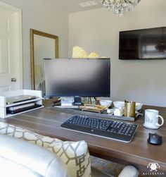 a desk with a computer monitor, keyboard and mouse on it in front of a mirror